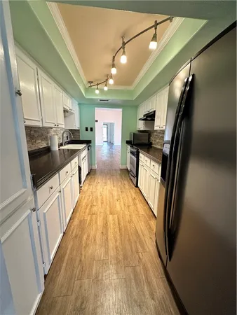 a kitchen with granite countertop a refrigerator a stove top oven and sink