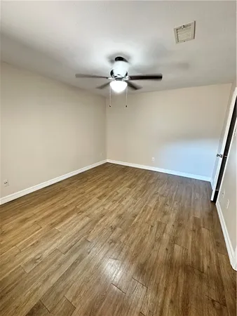 an empty room with wooden floor ceiling fan and window
