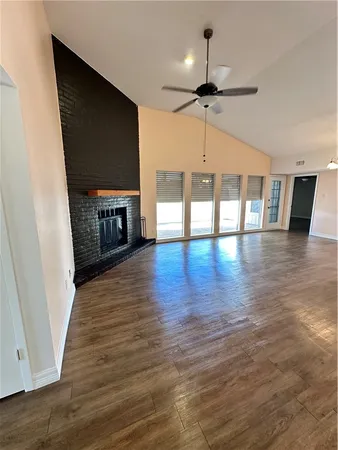 a view of a livingroom with fireplace wooden floor and a ceiling fan