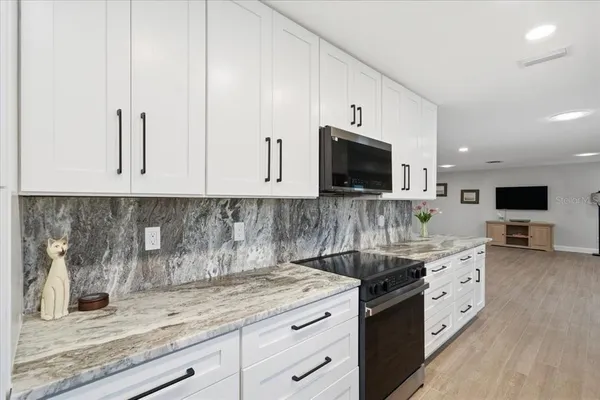 a kitchen with granite countertop white cabinets and stainless steel appliances