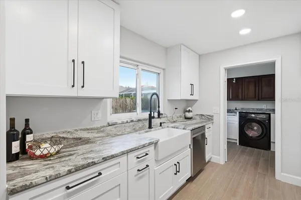 a kitchen with granite countertop a sink a stove and cabinets