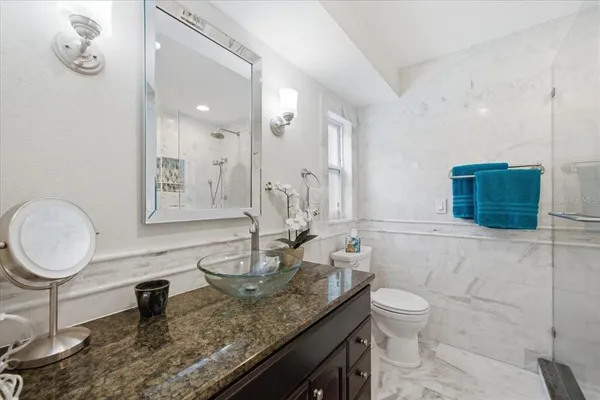 a bathroom with a granite countertop sink a toilet and a mirror
