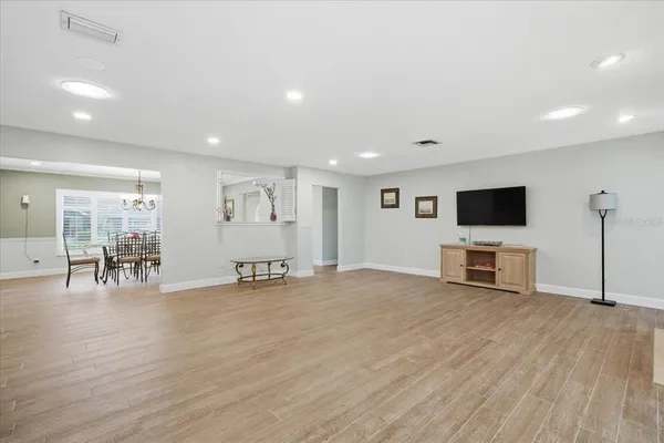 a view of an empty room with wooden floor and a flat screen tv