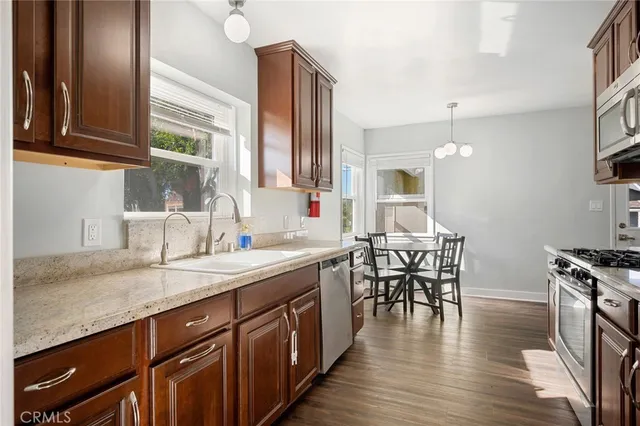 a kitchen with stainless steel appliances granite countertop a table chairs stove and sink