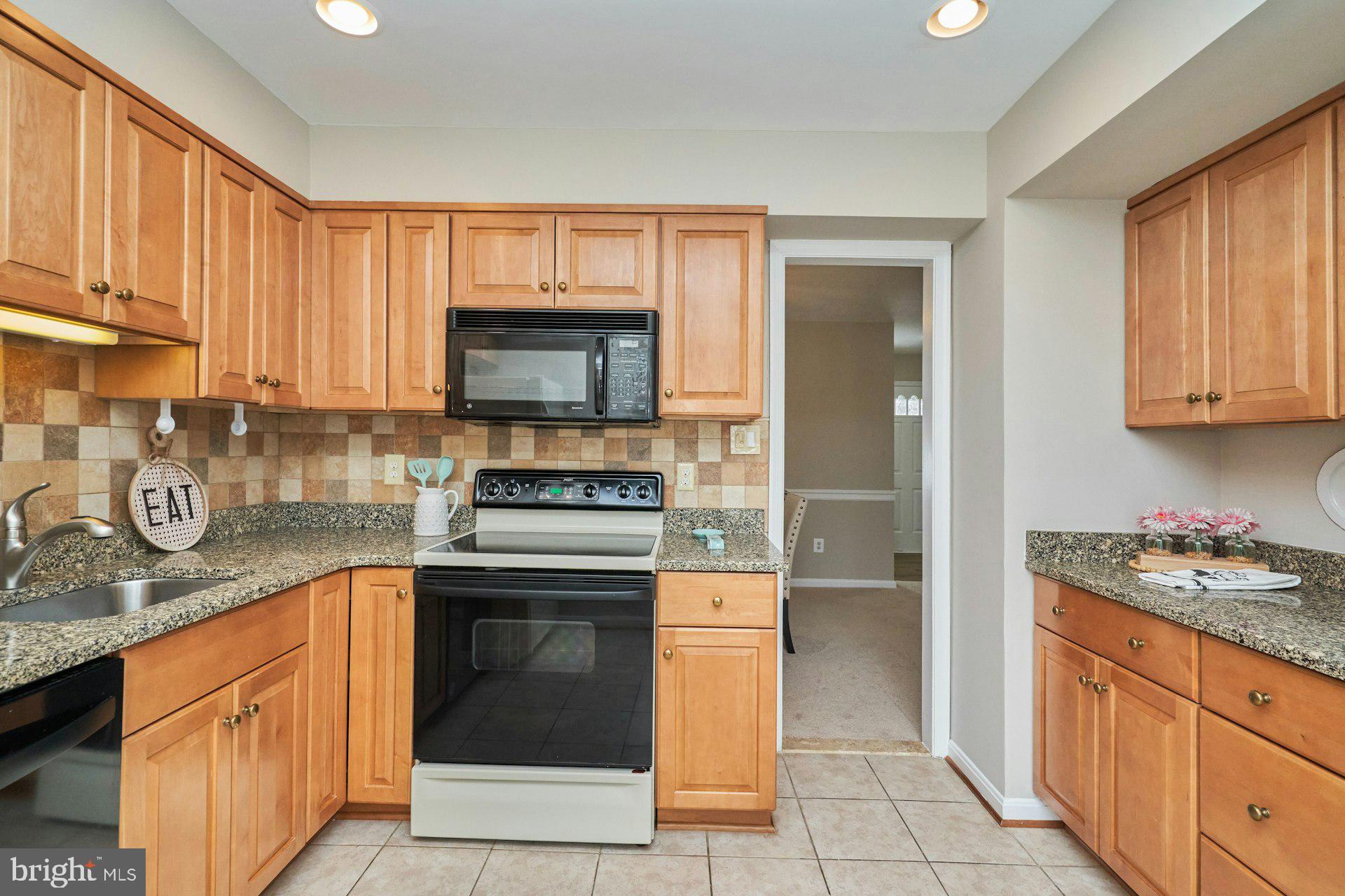 9634 Blincoe Court Burke, VA 22015 - Photo 16 of 53 a kitchen with granite countertop a stove top oven microwave and cabinets