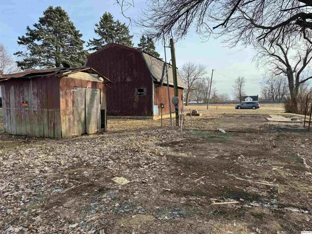 a backyard of a house with large trees and wooden fence