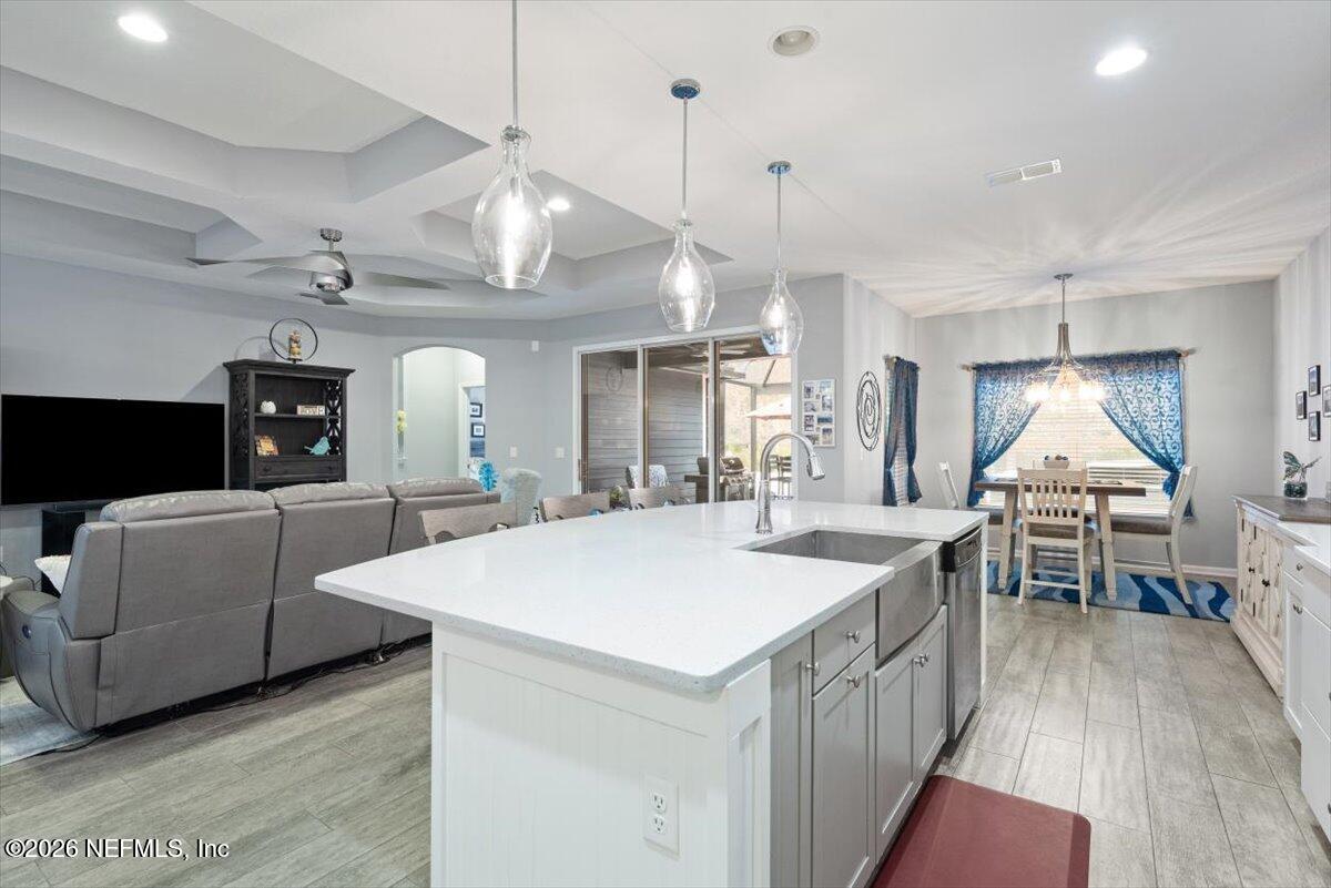 96085 Breezeway Court Yulee, FL 32097 - Photo 18 of 59 a large white kitchen with a large island oven a stove a sink a dining table and chairs with wooden floor