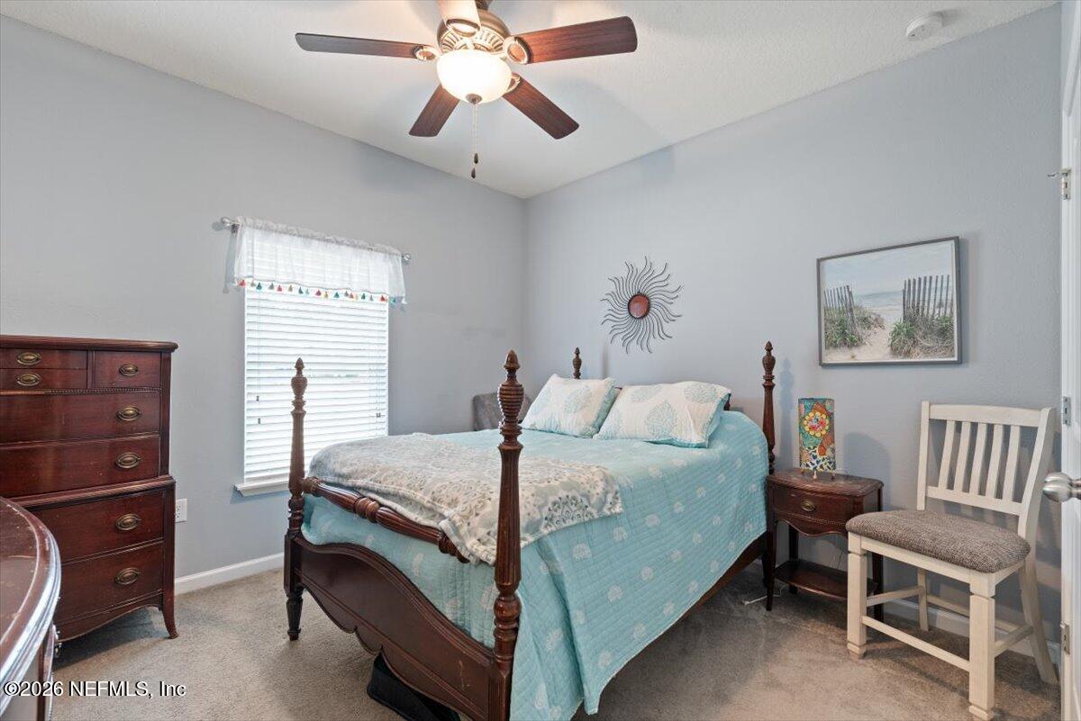 96085 Breezeway Court Yulee, FL 32097 - Photo 30 of 59 a bedroom with a bed and a chandelier