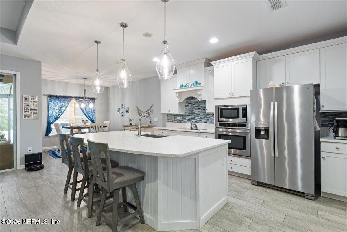 96085 Breezeway Court Yulee, FL 32097 - Photo 3 of 59 a kitchen with stainless steel appliances kitchen island a table chairs refrigerator and sink