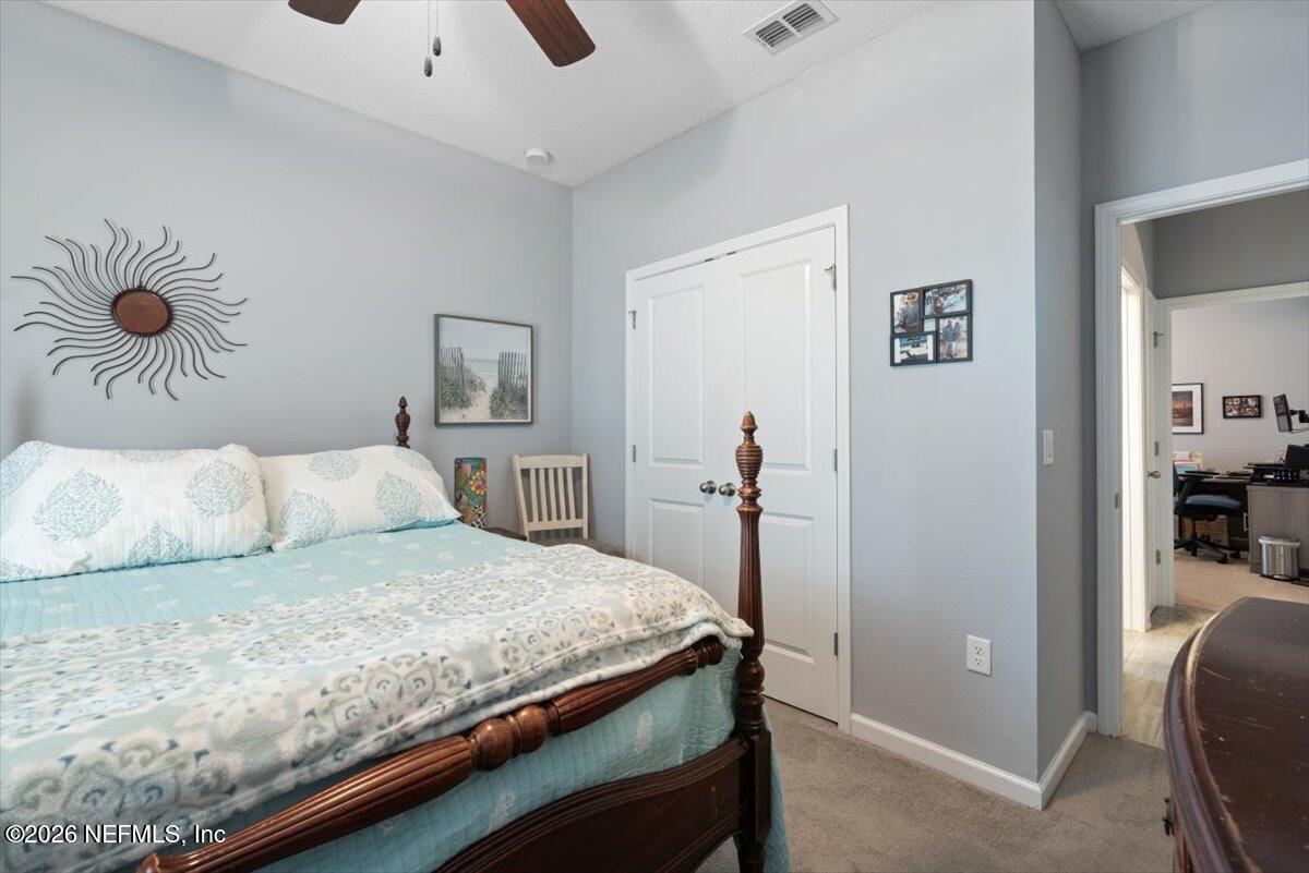 96085 Breezeway Court Yulee, FL 32097 - Photo 31 of 59 a bedroom with a bed and a chandelier