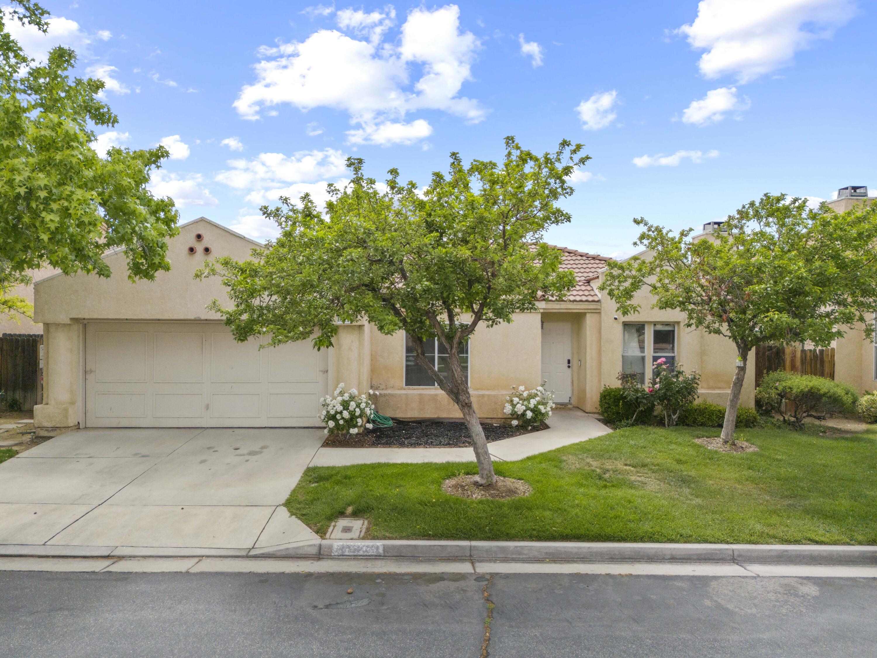 40131 La Cota Drive Palmdale, CA 93550 - Photo 2 of 26 a front view of a house with a garden and trees