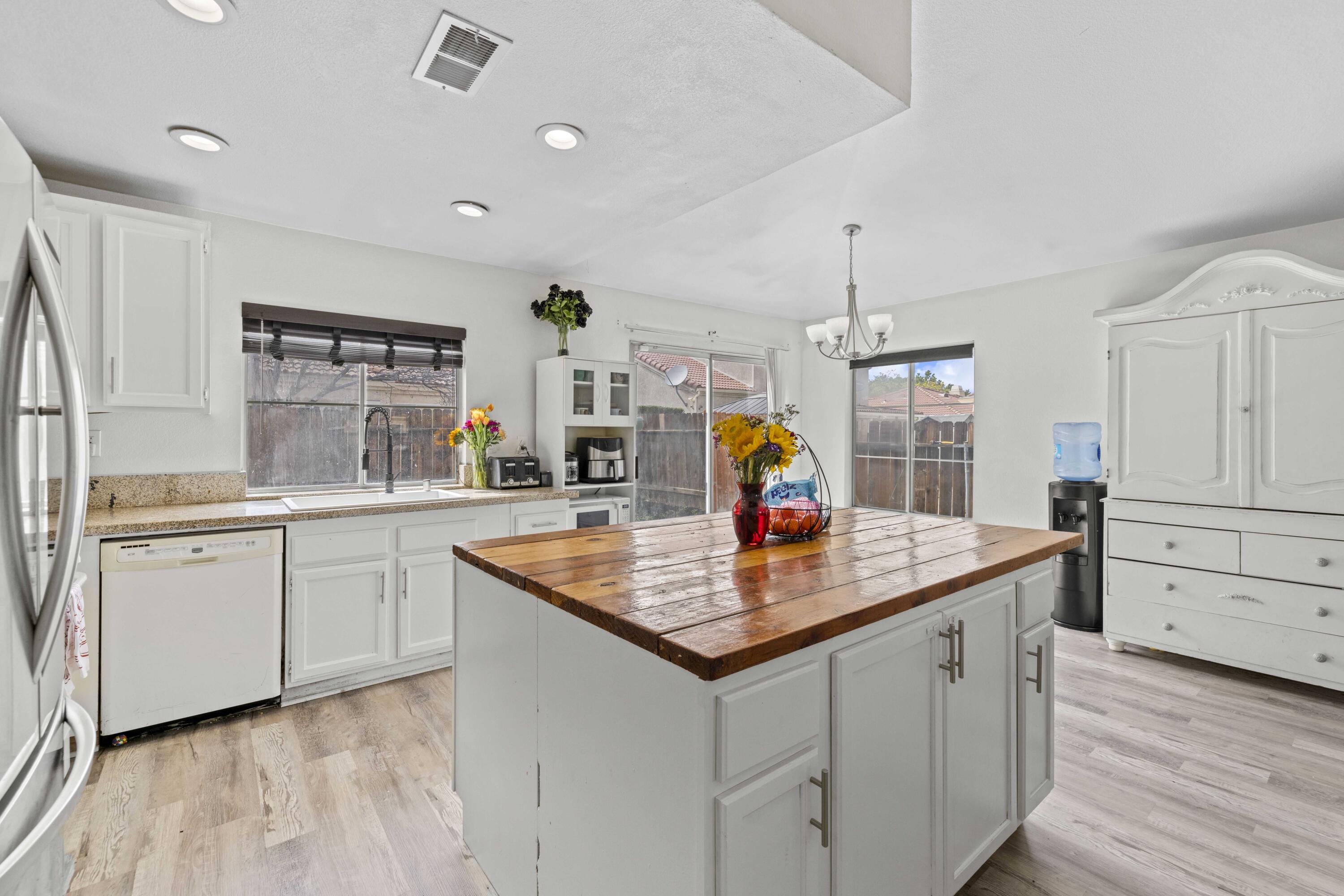 40131 La Cota Drive Palmdale, CA 93550 - Photo 7 of 26 a kitchen with stainless steel appliances granite countertop a sink dishwasher and white cabinets with wooden floor