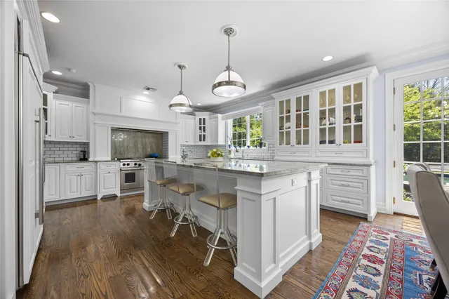 a kitchen with stainless steel appliances kitchen island granite countertop a stove a sink dishwasher a dining table and chairs with wooden floor