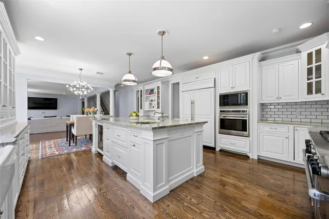 a large kitchen with stainless steel appliances kitchen island granite countertop a stove a sink a refrigerator and a fireplace