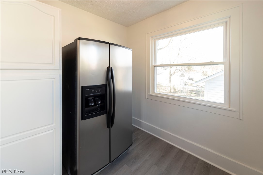 1022 North Howard Street Akron, OH 44310 - Photo 12 of 38 Kitchen with white cabinetry, dark hardwood / wood-style floors, and stainless steel fridge