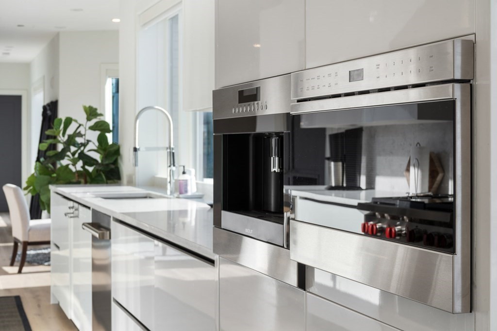 100 A Street, Unit 6 Boston, MA 02127 - Photo 12 of 37 a kitchen with stainless steel appliances kitchen island granite countertop a refrigerator a stove and a dining table with wooden floor