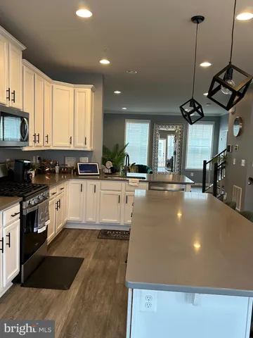 a kitchen with stainless steel appliances a stove a sink a oven a kitchen island with white cabinets