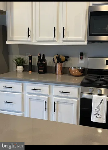 a kitchen with stainless steel appliances granite countertop a stove a sink and white cabinets