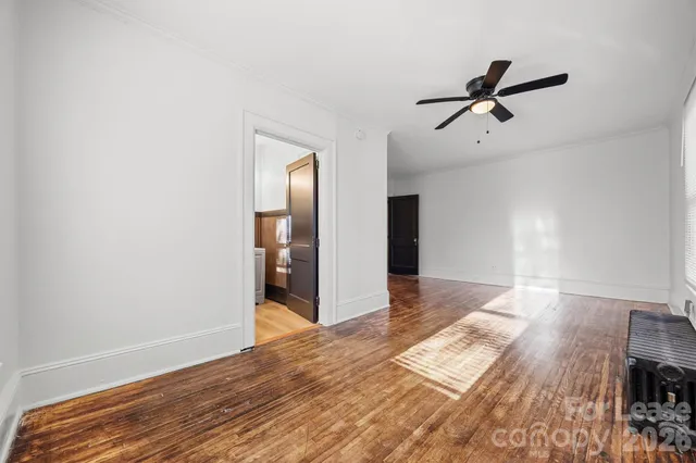 a view of empty room with wooden floor and window