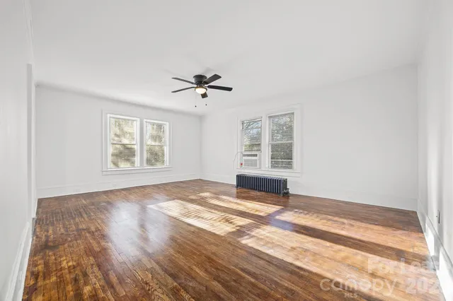 a view of an empty room with a window and wooden floor