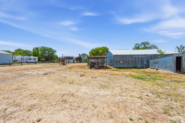 3732 Campbell Road Tooele, UT 84074 - Photo 59 of 69 Expansive outdoor space featuring multiple outbuildings, including a large corrugated metal structure with a pitched roof and a smaller open-sided shed