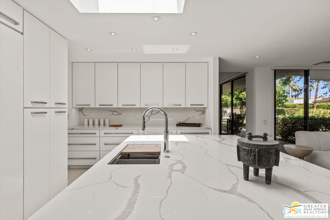 6 Trojan Court Rancho Mirage, CA 92270 - Photo 21 of 51 a kitchen with stainless steel appliances granite countertop a sink a stove and white cabinets with wooden floor