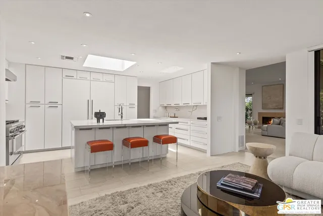 a living room with furniture a rug and kitchen view