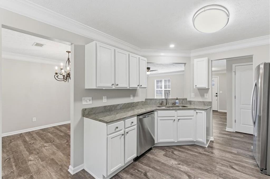 125 Governor Lane Temple, GA 30179 - Photo 21 of 57 a kitchen with a sink dishwasher a refrigerator and white cabinets with wooden floor