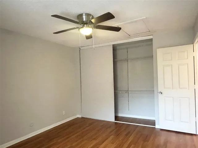 an empty room with wooden floor closet and ceiling fan