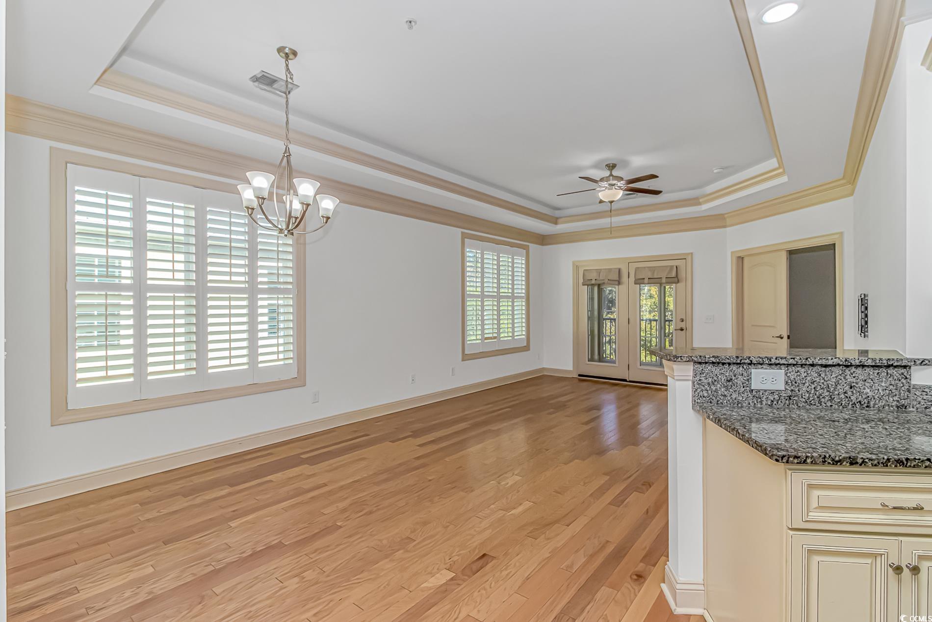 128 Puffin Drive, Unit 3A Pawleys Island, SC 29585 - Photo 18 of 30 Kitchen featuring crown molding, dark stone counters, a tray ceiling, decorative light fixtures, and light wood finished floors