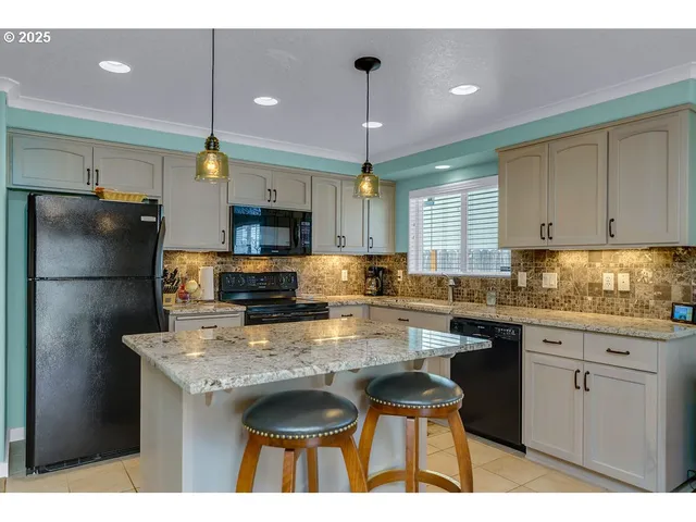 a kitchen with kitchen island granite countertop a sink cabinets and stainless steel appliances