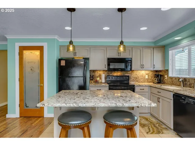 a kitchen with granite countertop a stove a kitchen island a sink cabinets and wooden floor