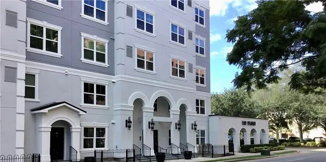 a front view of a building with lot of cars and trees