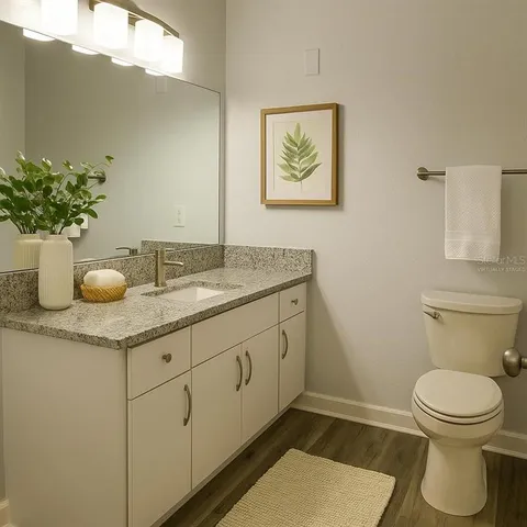 a bathroom with a granite countertop sink and a toilet