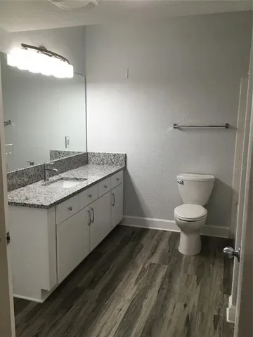 a bathroom with a granite countertop toilet a sink and a mirror
