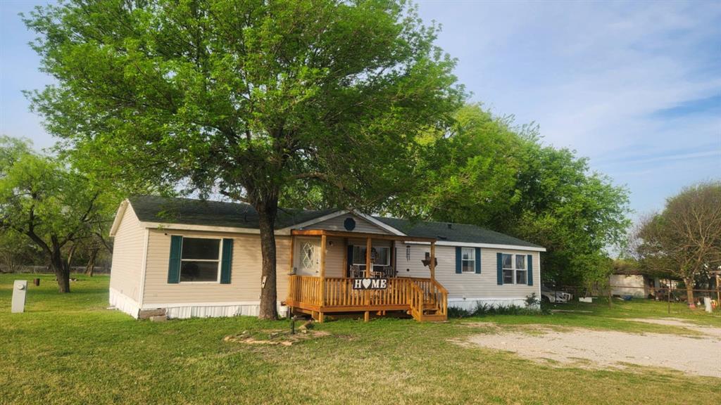 View of front of home with a wooden deck and a front yard