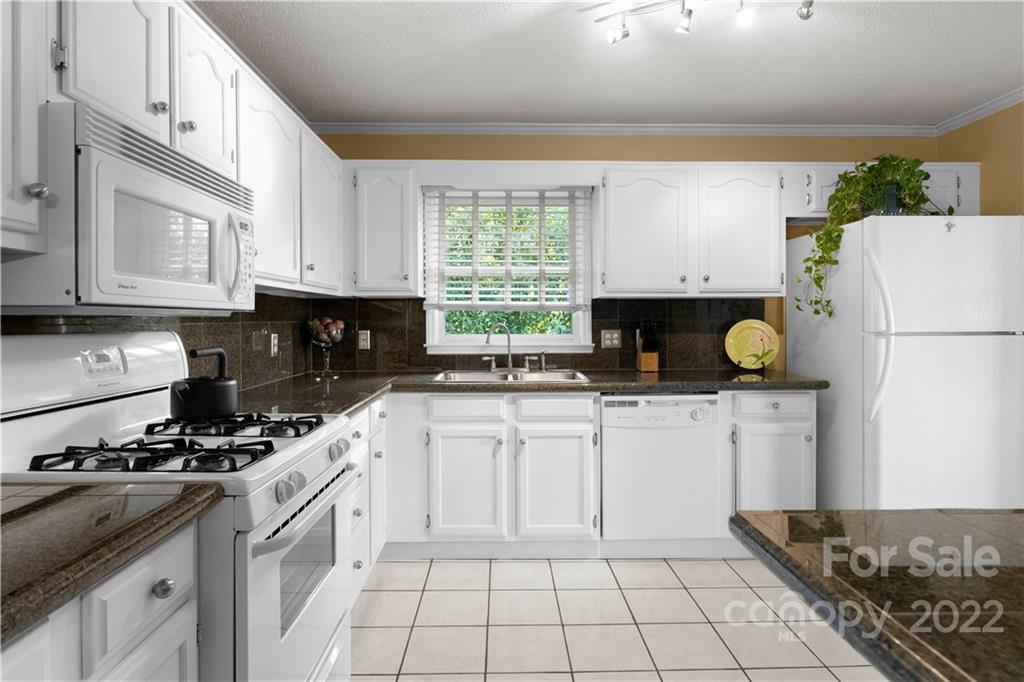 1705 Tyvola Road Charlotte, NC 28210 - Photo 13 of 40 a kitchen with a refrigerator sink and white cabinets