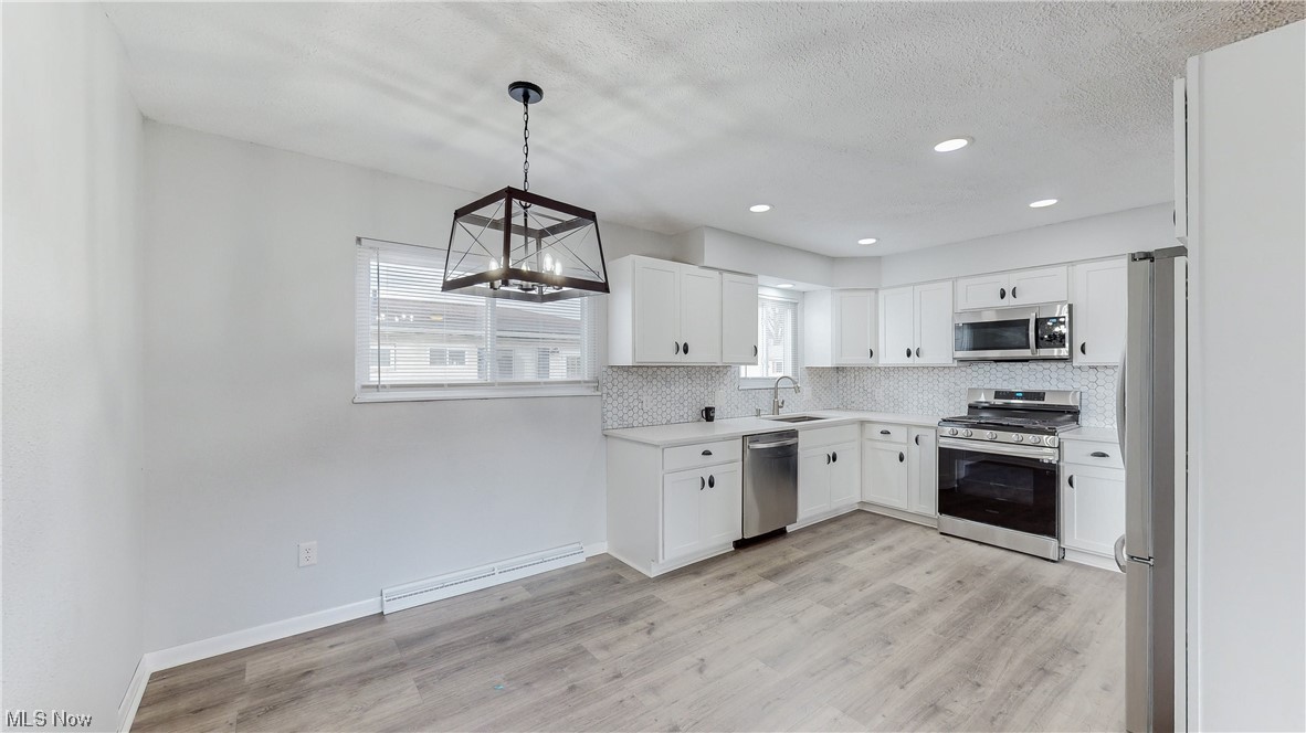 1466 Scenic Way Akron, OH 44310 - Photo 6 of 35 Kitchen featuring white cabinets, hanging light fixtures, light wood-type flooring, and stainless steel appliances