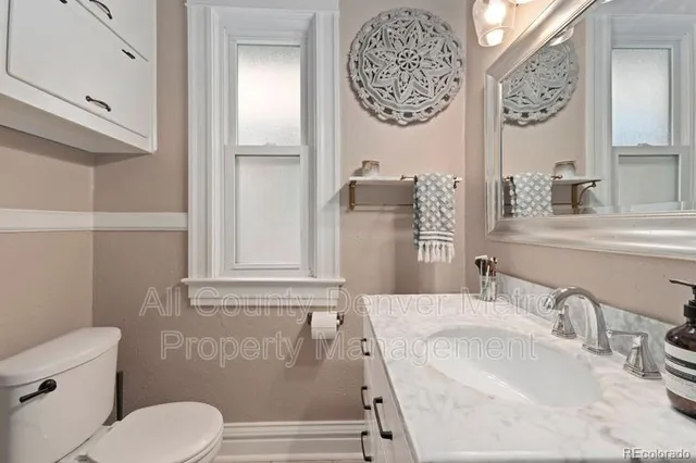 a bathroom with a granite countertop sink mirror vanity and toilet