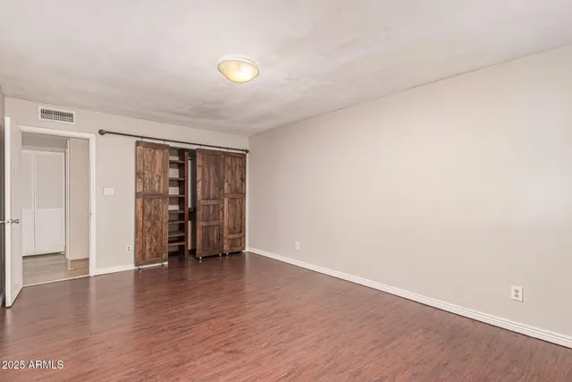 a view of an empty room with wooden floor and closet