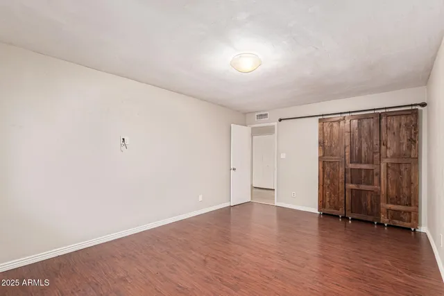 an empty room with wooden floor and closet