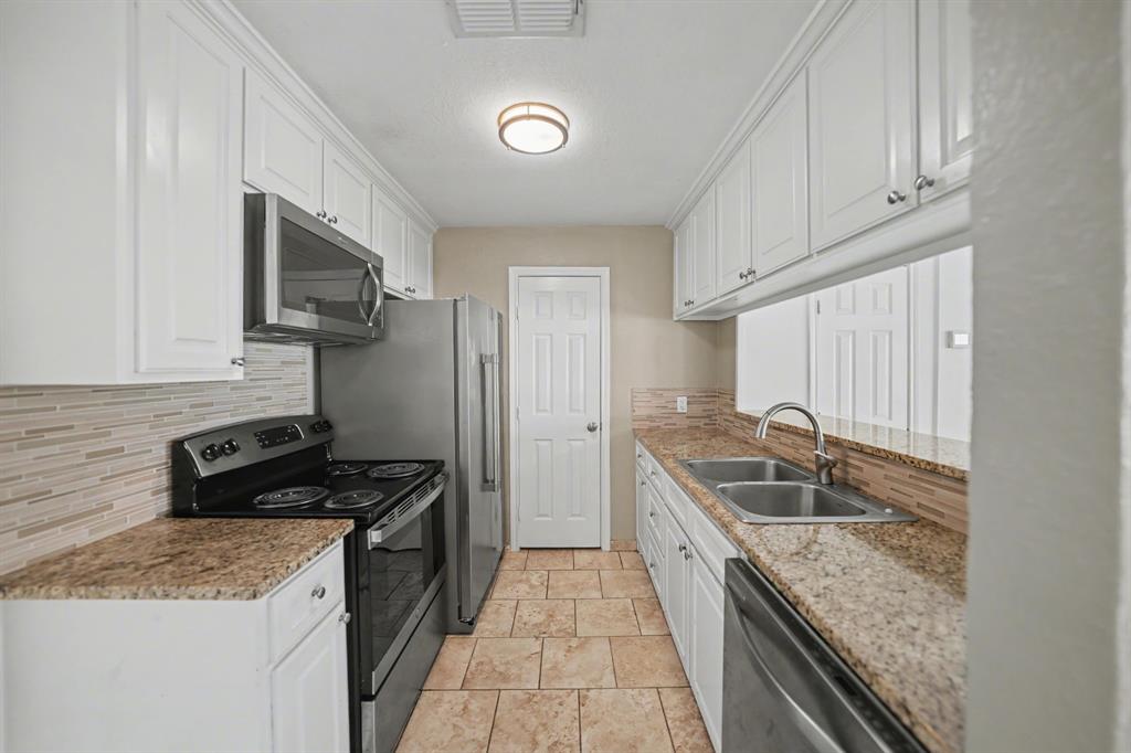 6925 Calender Road, Unit A Arlington, TX 76001 - Photo 12 of 19 a kitchen with granite countertop stainless steel appliances a sink stove top oven and cabinets