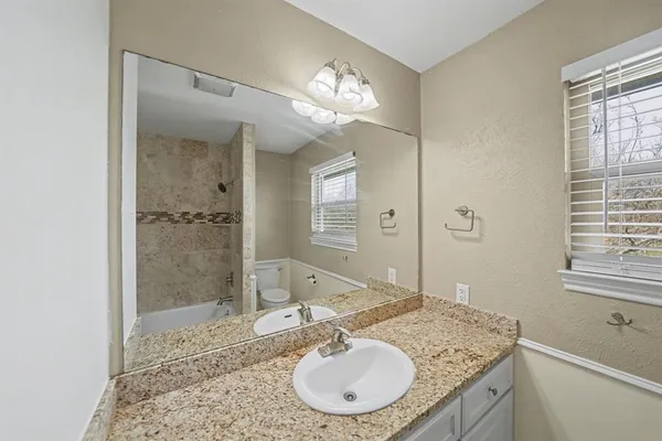 a bathroom with a granite countertop sink a mirror and a shower
