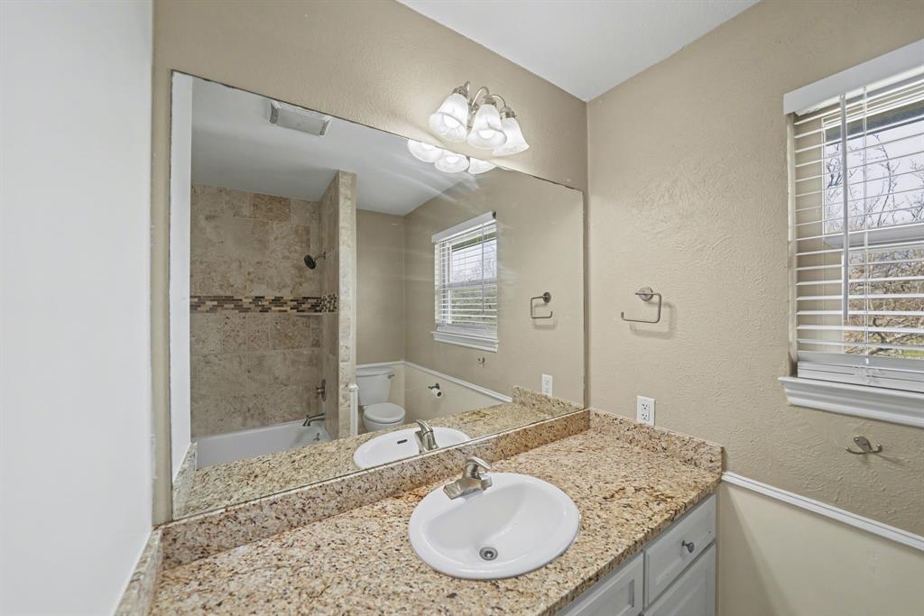 6925 Calender Road, Unit A Arlington, TX 76001 - Photo 15 of 19 a bathroom with a granite countertop sink a mirror and a shower