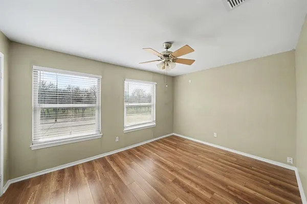 a view of an empty room with a window and wooden floor