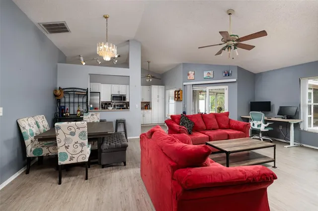 a living room with furniture kitchen view and a chandelier