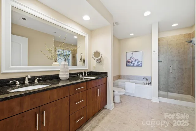 a bathroom with a granite countertop double vanity sink a mirror and a bathtub