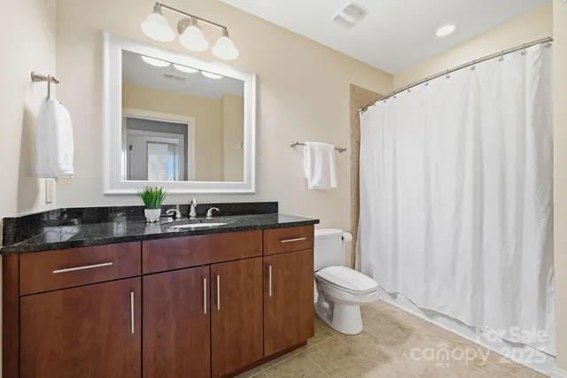 a bathroom with a granite countertop sink a toilet and a mirror
