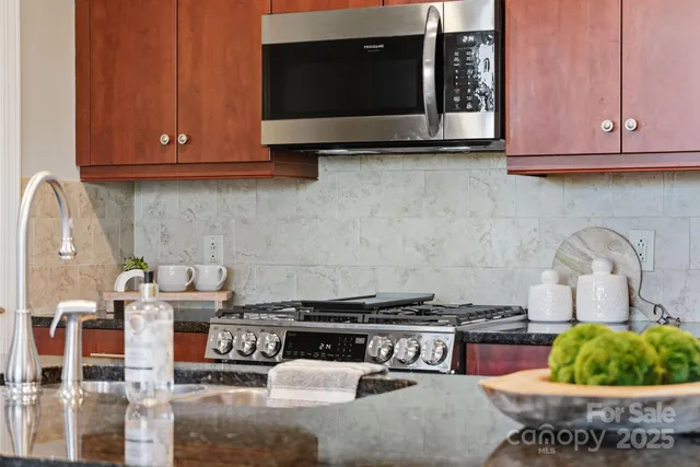 a kitchen with stainless steel appliances granite countertop a stove and a microwave with cabinets