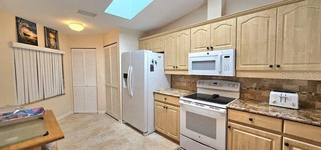 a kitchen with granite countertop a sink a stove and cabinets